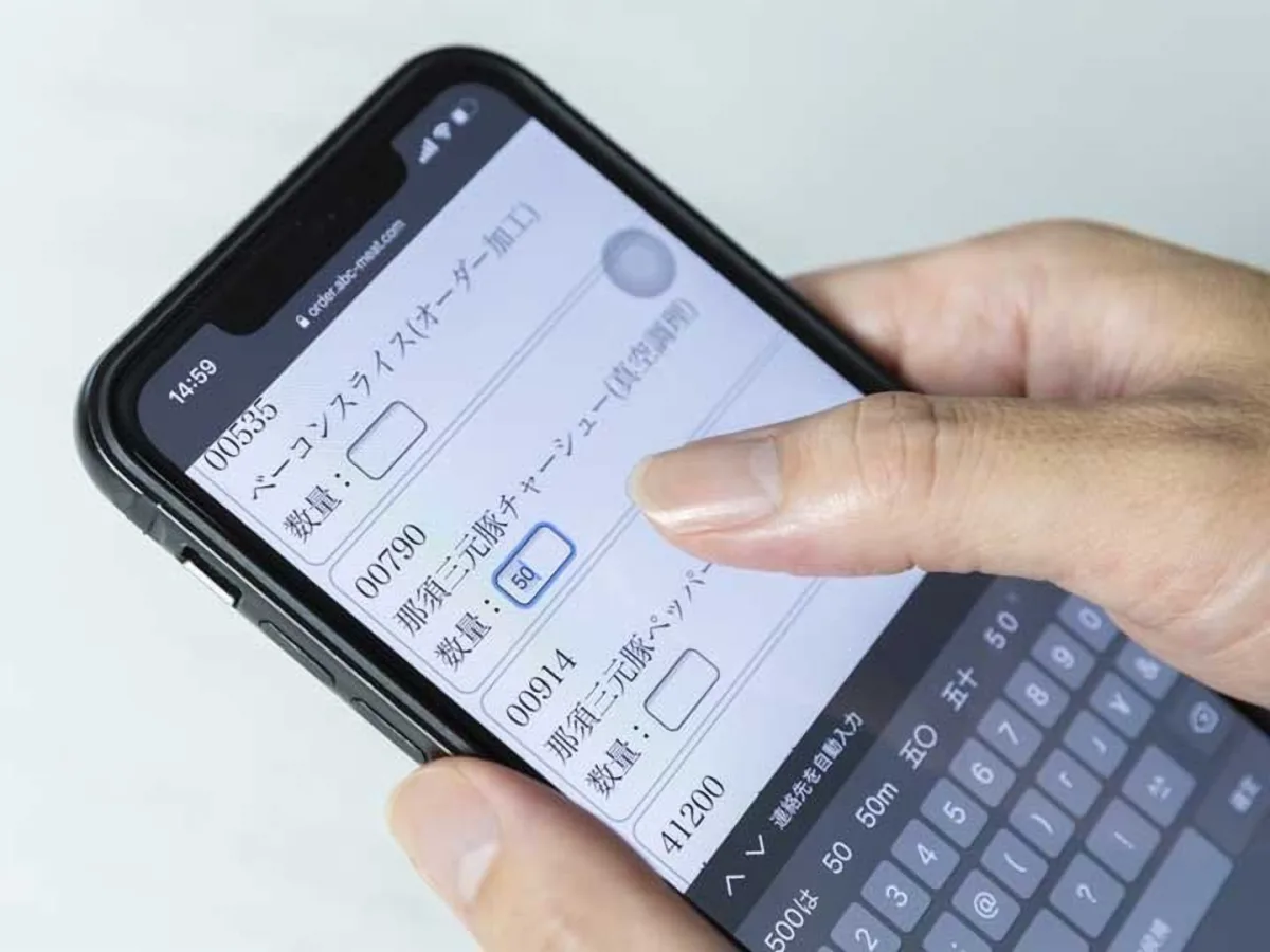 スマートフォンの画面で、肉の注文数量を入力する手元