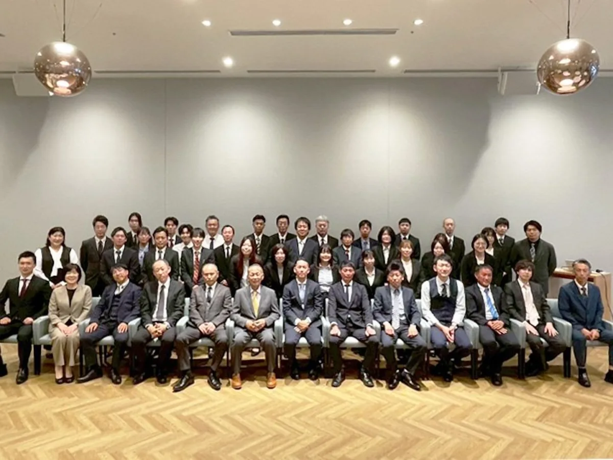 会場に並んで記念撮影をする、スーツ姿の社員たち