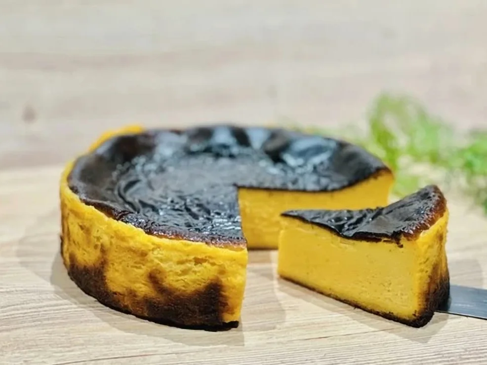 表面を黒く焼き上げたバスクチーズケーキと、切り分けた一切れ