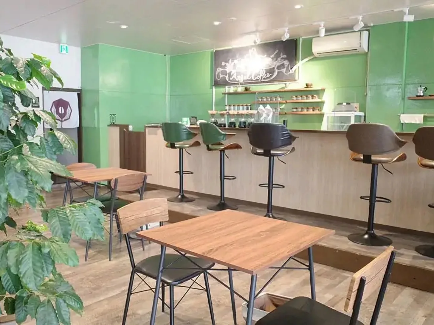 緑の壁と木のカウンター、テーブル席が並ぶエンジェルコーヒーの店内
