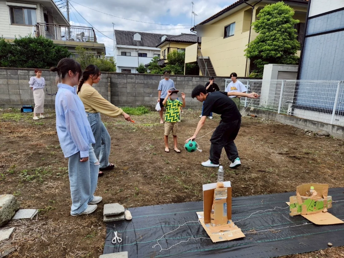 たぬき亭の庭で、ボールを使った遊びを楽しむ学生と地域の人たち