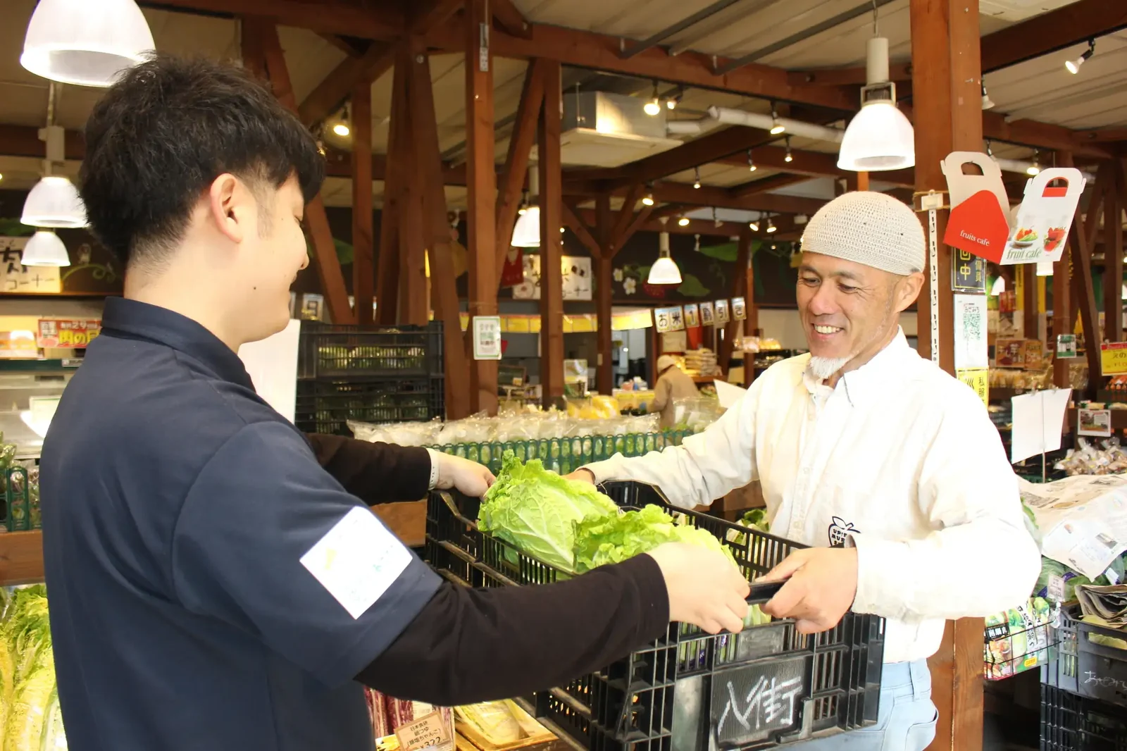 生産者が育てた野菜をスタッフへ手渡す様子