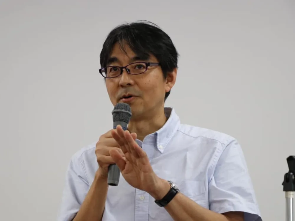 マイクを手に、身振りを交えて語る上岡裕さん