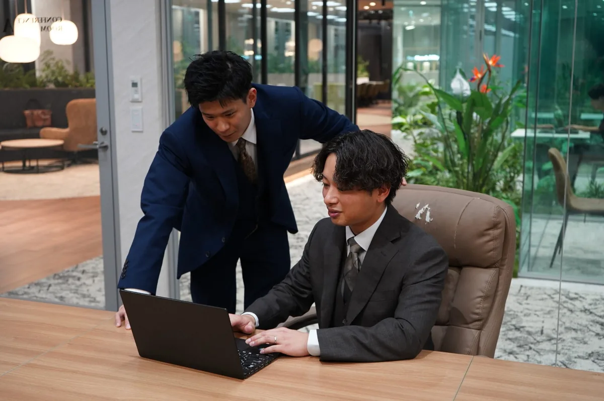 パソコンの画面を一緒に見ながら、先輩が後輩に助言する様子