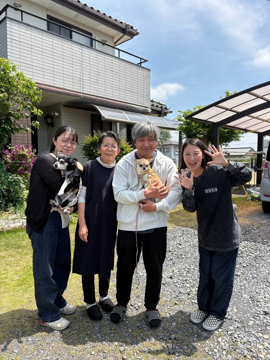 家の前で、犬を抱いた人たちがそろって並ぶ
