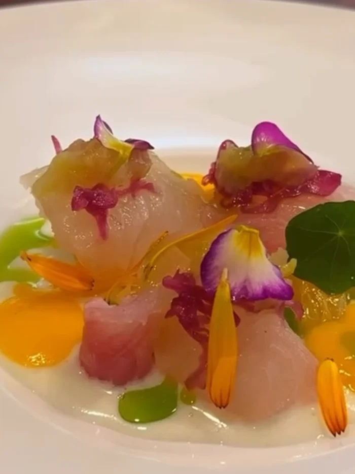 白い皿に花びらを散らした、白身魚の前菜