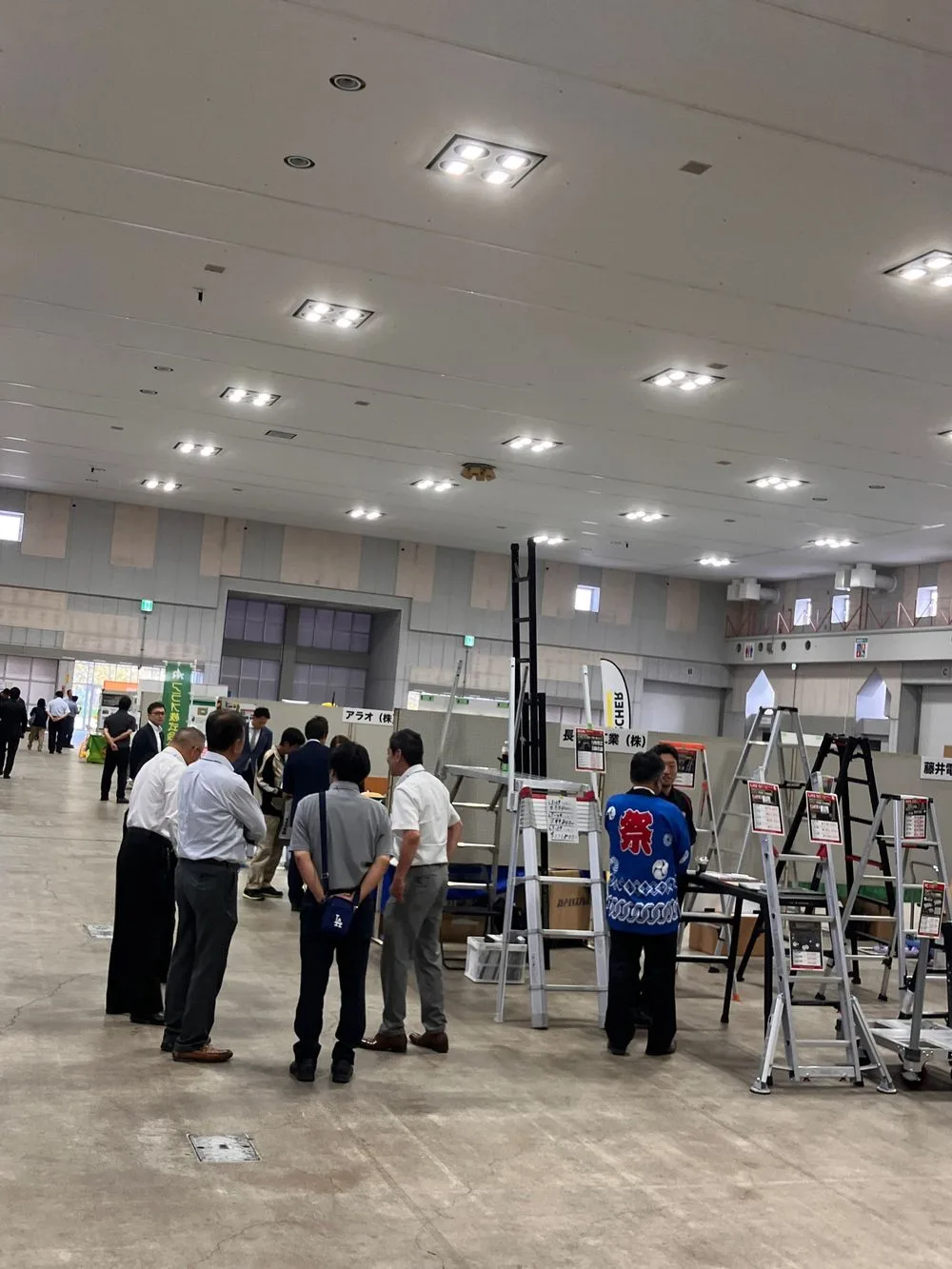 展示会の会場で機器の説明を聞く来場者