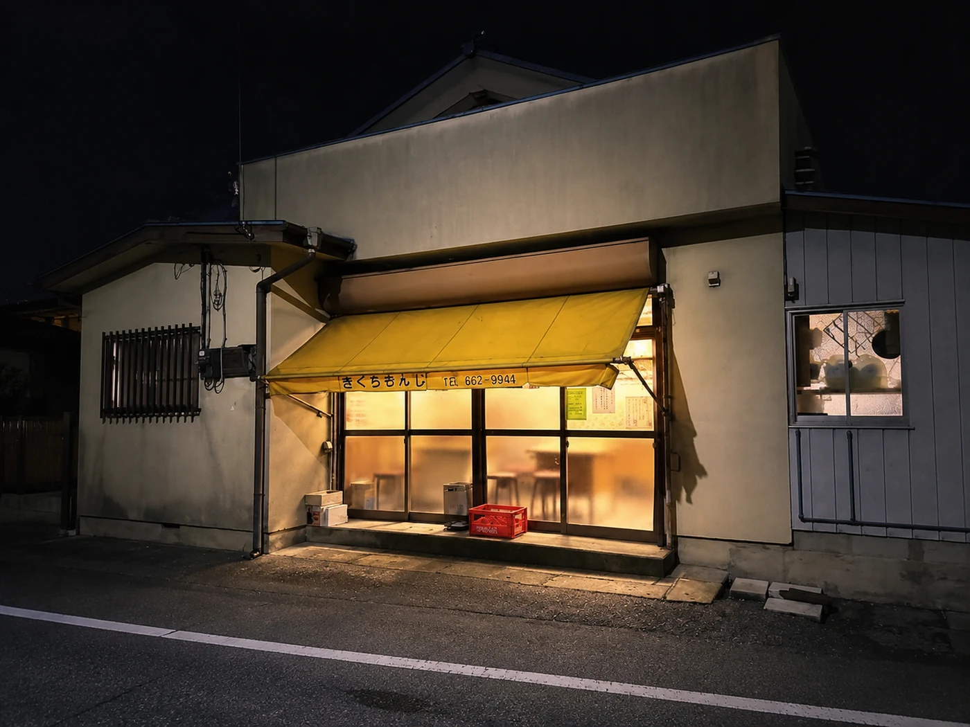 夜、灯りがともる「きくちもんじ」の外観
