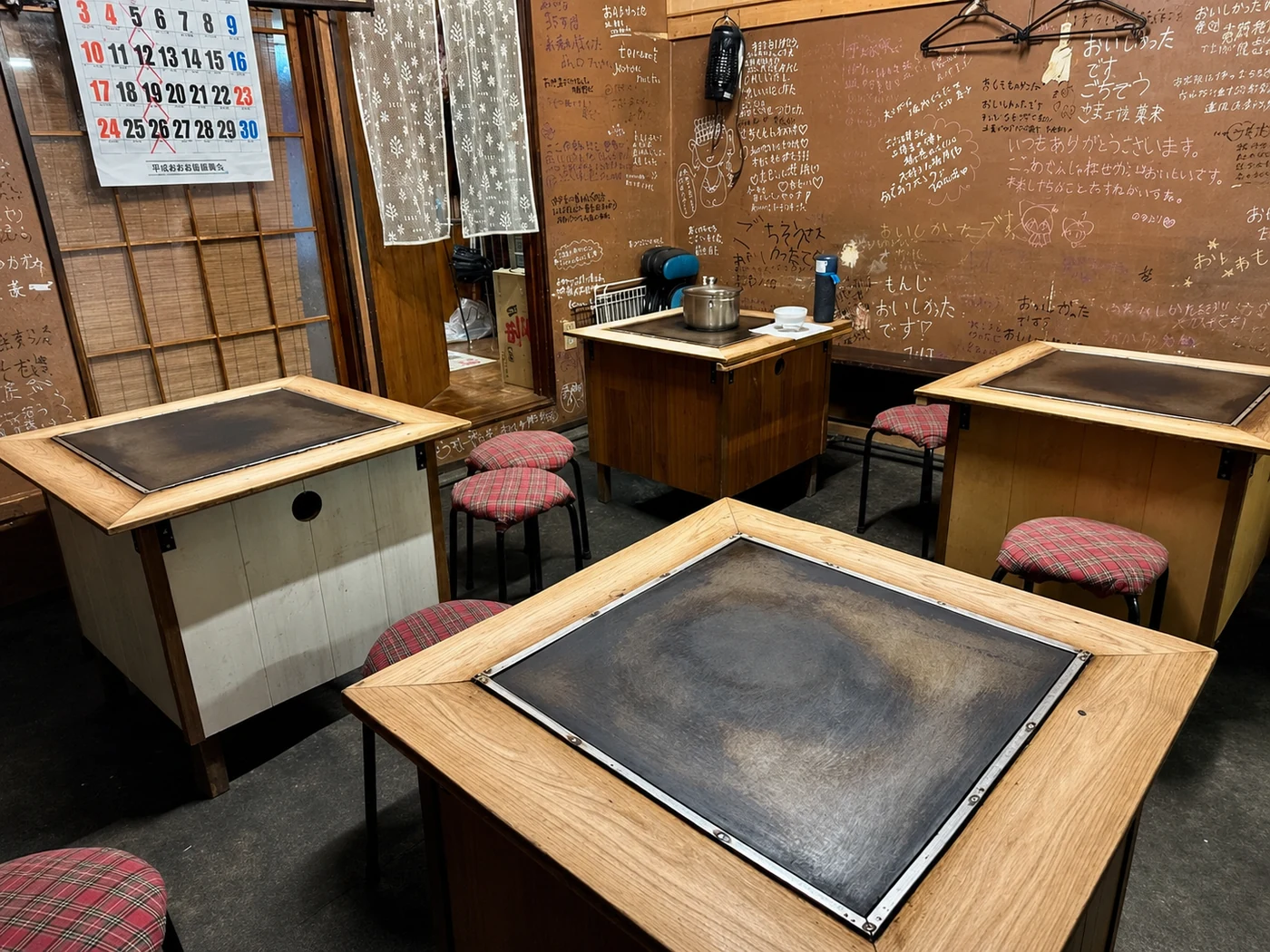鉄板の並ぶ店内と、壁に書き込まれた来店者のメッセージ