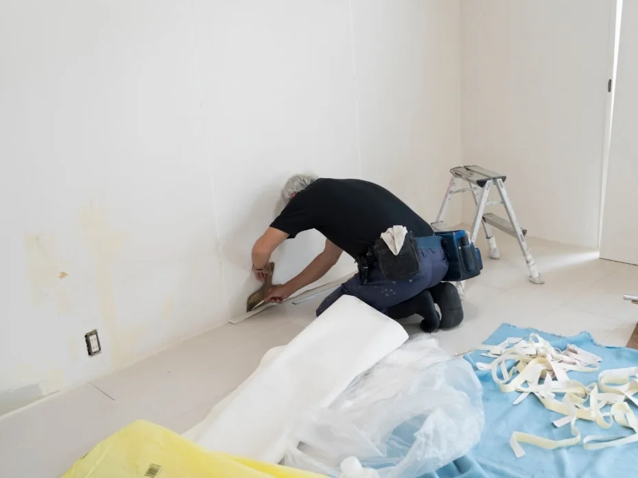 職人が壁にクロスを貼っている作業中の部屋