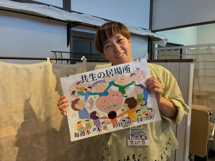 「共生の居場所」の案内を手にするスタッフ