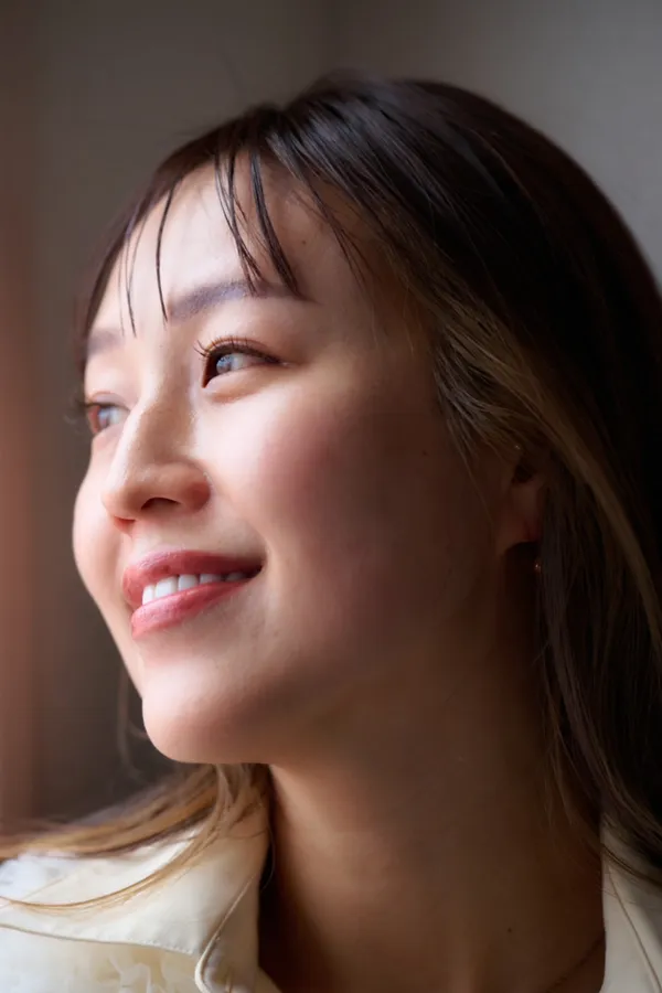 窓からの光の中で、横を向いてほほえむまきえ氏