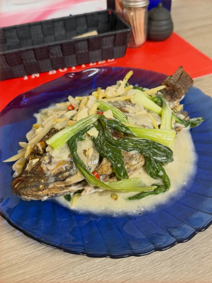 青いガラス皿に盛った、魚と青菜のクリーム煮