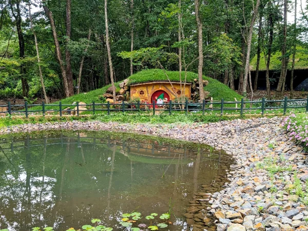 草屋根の小さなコテージと池のある、北欧風の庭園