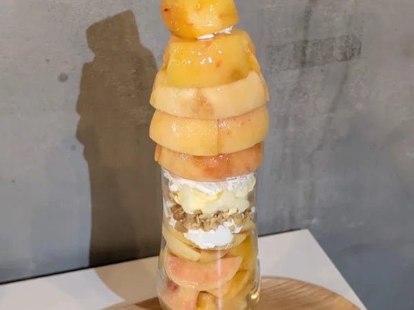 完熟の桃を丸ごと重ねた背の高いパフェ