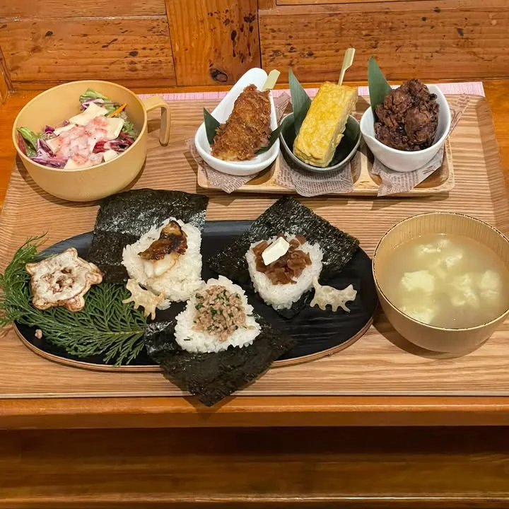猫の形のせんべいを添えた、3種のおにぎりと小鉢、汁物のコラボメニューの膳