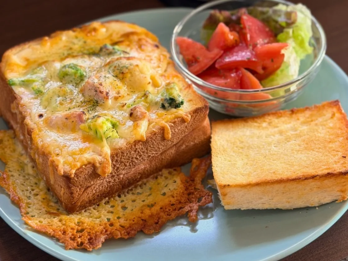 チキンとホワイトシチューを詰めて焼いたグラタンパンと、トマトのサラダ