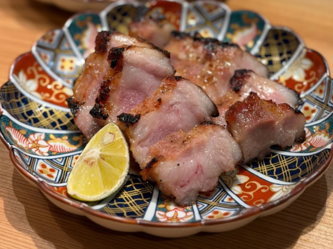 絵皿に盛った、香ばしく焼いた豚肉とレモン