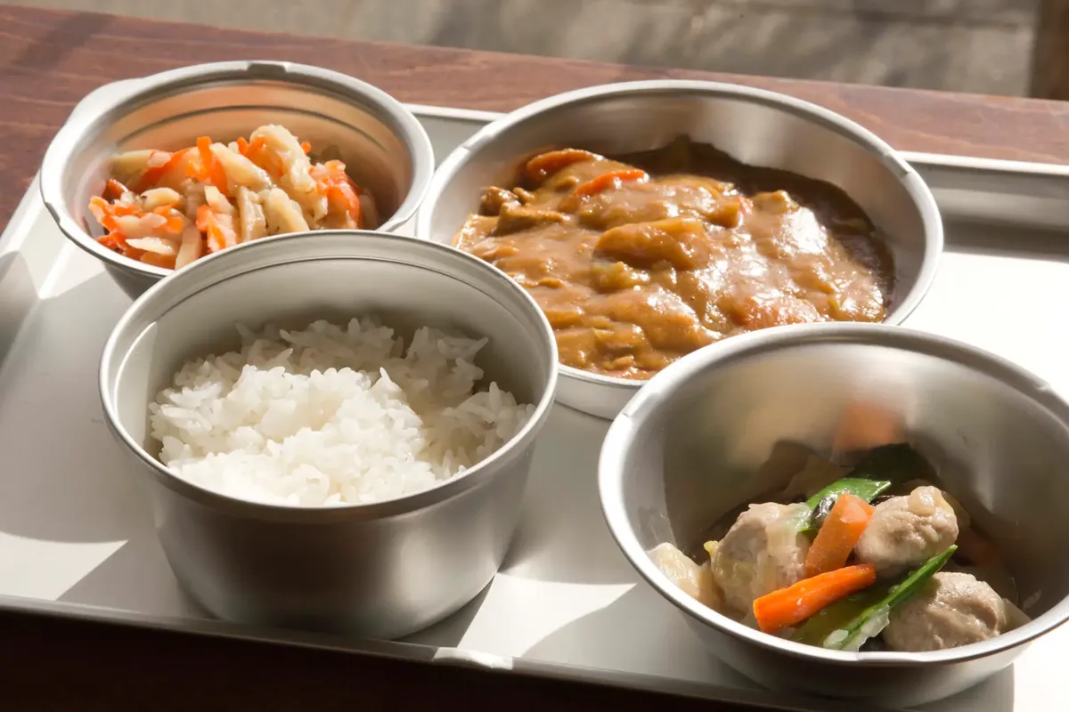 トレイに盛り付けられた給食。ご飯、カレー、和え物、煮物