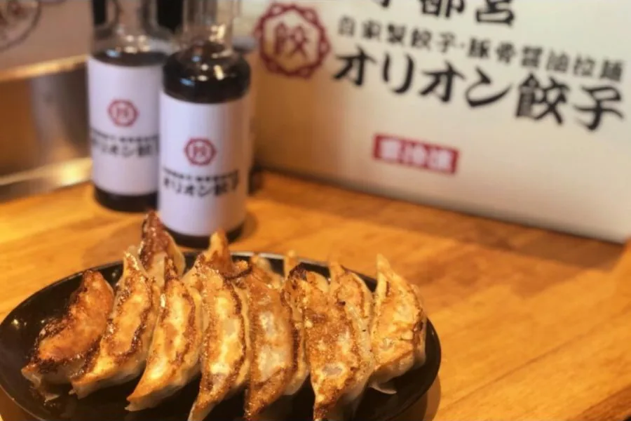 焼き上げた餃子の皿と、オリオン餃子のたれ・冷凍便の箱