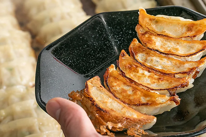 焼き上がった餃子を皿に盛り、客席へ運ぶスタッフの手元