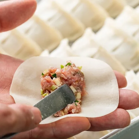 手のひらの皮に、へらで餡をのせて包む作業