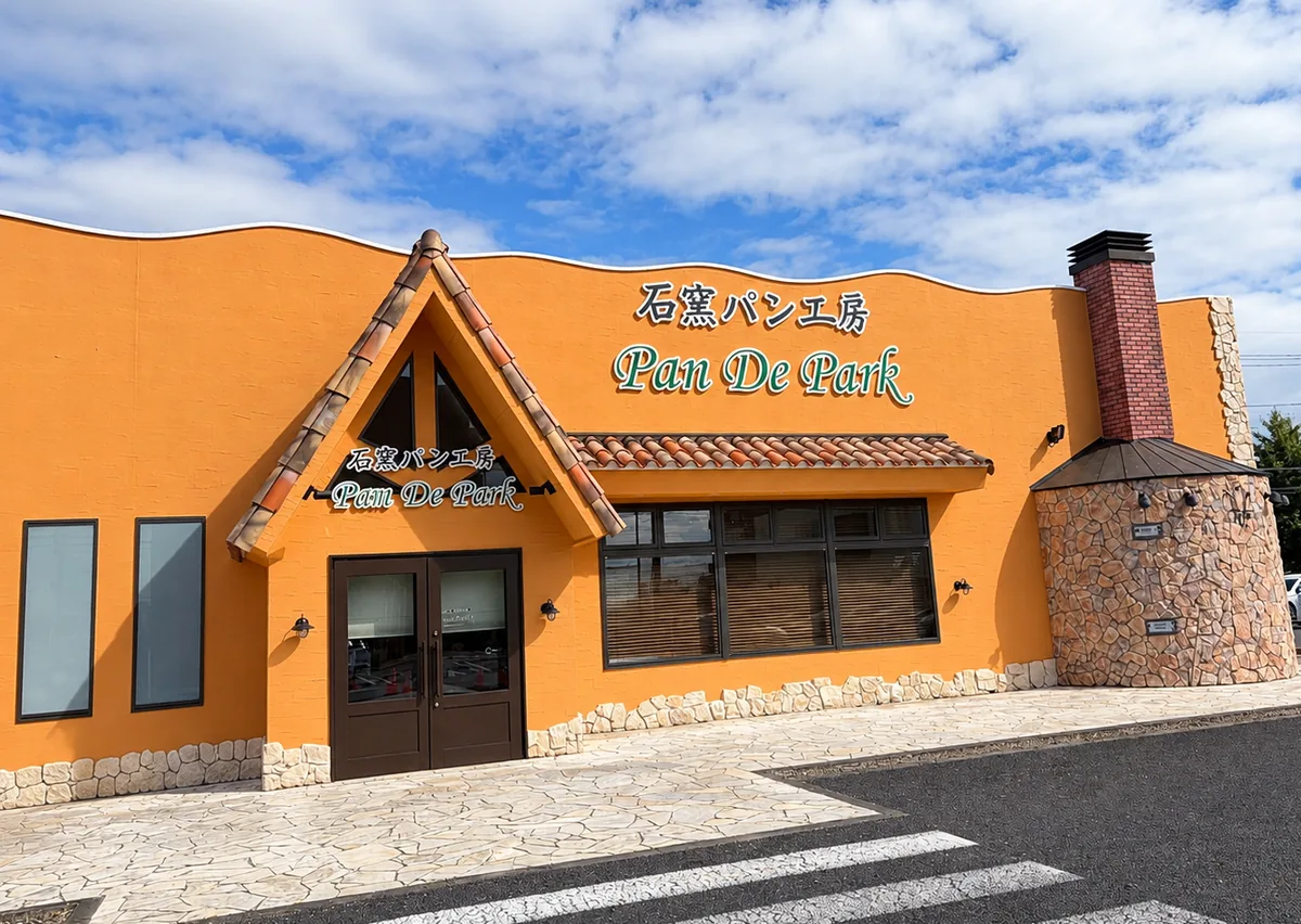 オレンジ色の壁と三角屋根の入口がある本店の正面