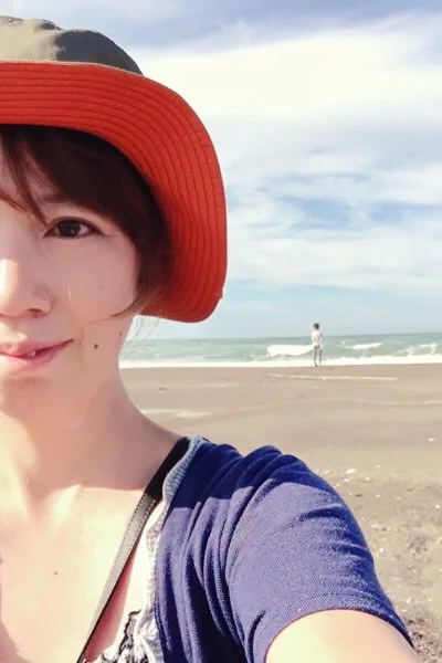 赤い帽子をかぶり、海辺で笑顔を見せるとちぎびよりの運営者しょう