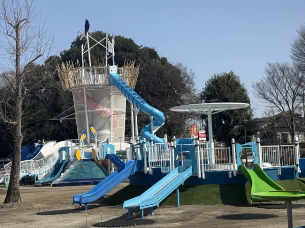 青空の下、滑り台やタワーが並ぶ公園の大型遊具