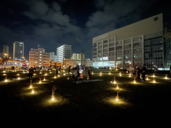 夜の広場に、小さな灯りがいくつも並ぶ風景