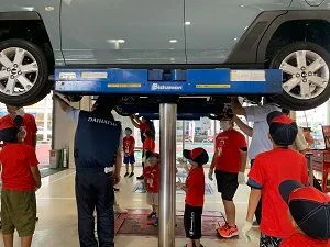 リフトで上げた車の下を見学する子どもたち
