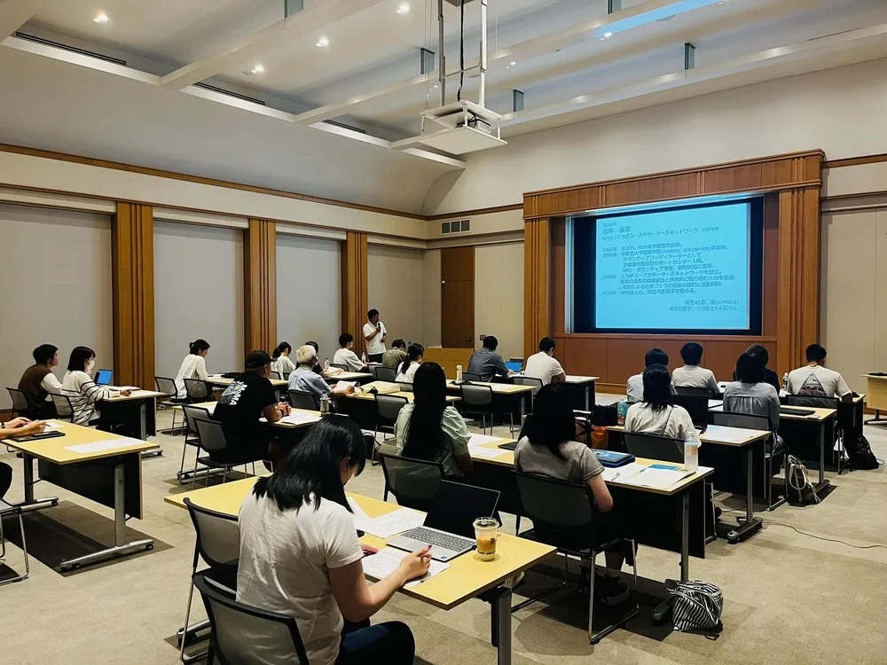 会場でスクリーンの資料を見ながら話を聞く参加者たち