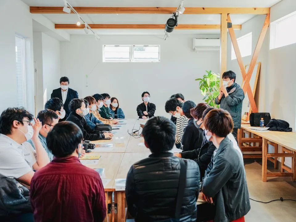 テーブルを囲み、資料を見ながら話し合う若者と参加者