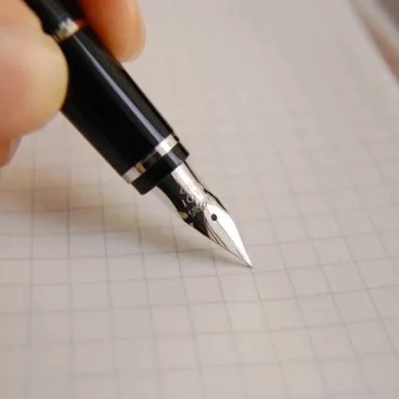 方眼紙の上で万年筆のペン先を試している手元