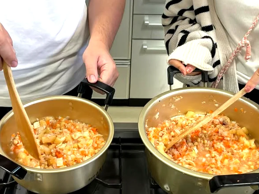 二つの鍋でしもつかれを煮込みながら木べらでかき混ぜる学生たちの手元