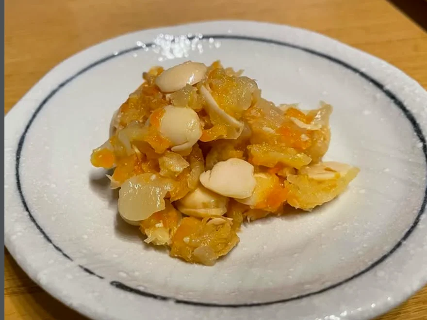 白い皿に盛り付けたしもつかれ。大根おろし・にんじん・大豆が混ざり合う